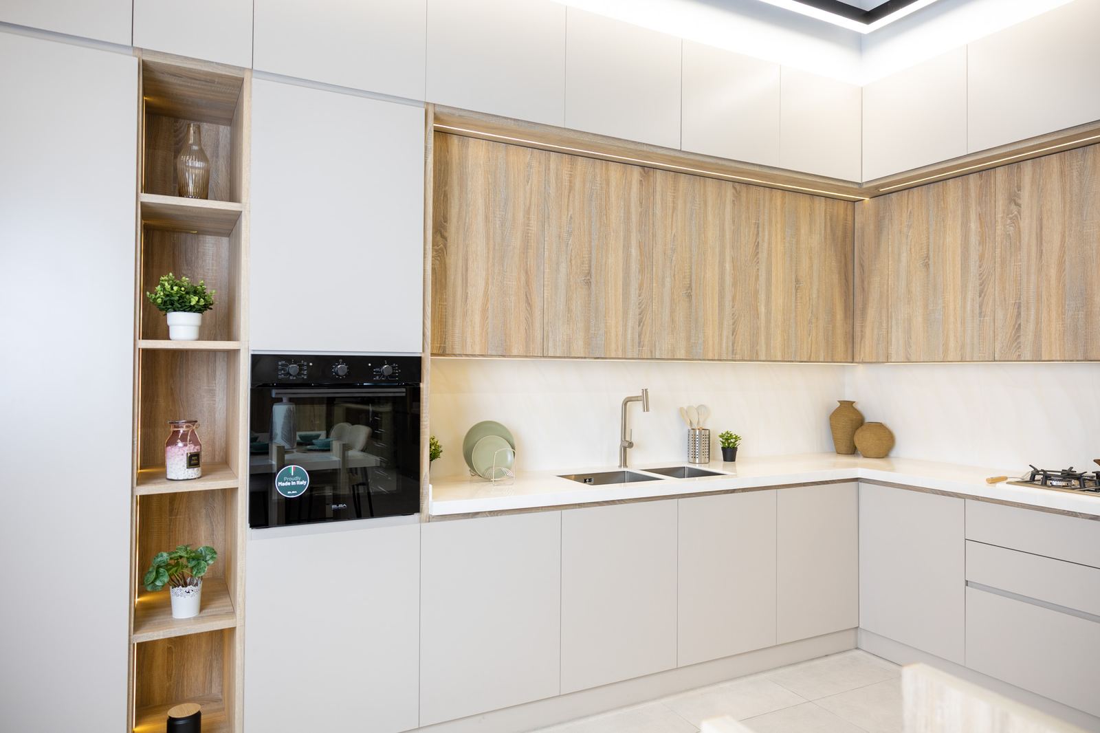 Kitchen with light wall cabinets, open wooden shelves and a tall oven unit